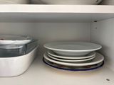 many plates and bowls on the shelves in the kitchen