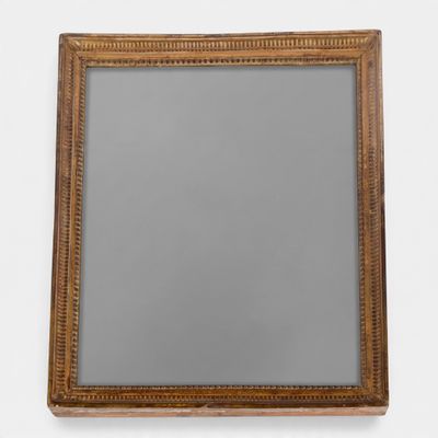 an antique wooden mirror with a gold frame on a white wall