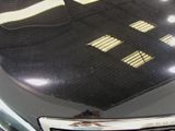 a close up of a car ' s hood with a reflection of a building on it