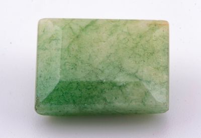un gros plan d'une pierre de jade verte sur une surface blanche