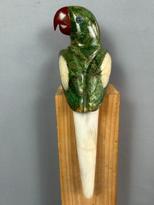 statue représentant un perroquet vert perché sur un morceau de bois