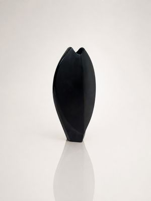 a black vase that is sitting on a white surface