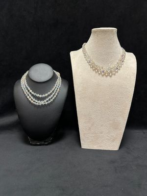 a white mannequin with pearls and a necklace on a black background