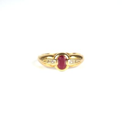 gros plan d'une bague en or avec un rubis et des diamants