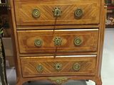 a small chest of drawers in a room with pictures on the wall