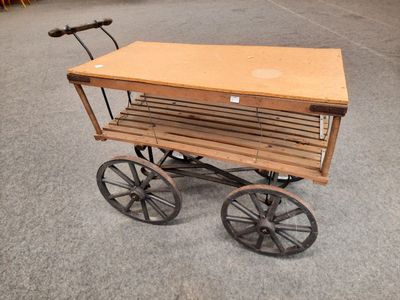 une petite charrette en bois munie d'un plateau en bois et de roues