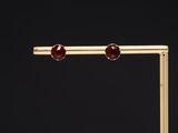 a pair of gold and garnetite earrings on a black background