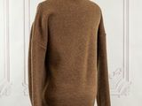 brown sweater on a mannequin stand in front of a white wall