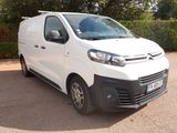 La camionnette blanche est garée sur le parking, près d'une haie.