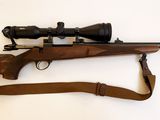 un vieux fusil muni d'une lunette et d'une sangle, posé sur une surface blanche