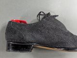 a pair of grey sued shoes with red soles on a gray surface