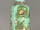 a green vase with flowers on it on a table