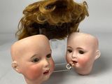 two heads of dolls with hair on a stand