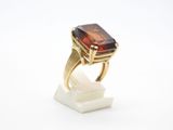 un gros plan d'une bague en or sertie d'une grosse pierre brune