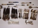 many different types of silverware and spoons laid out on a table