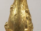 a gold vase that is sitting on a wooden table