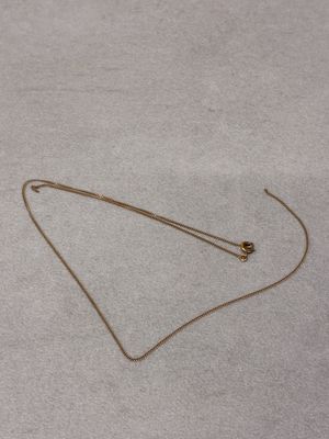 a gold necklace with a ball on it laying on the floor