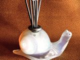 a glass vase with a bird on top of it on a table
