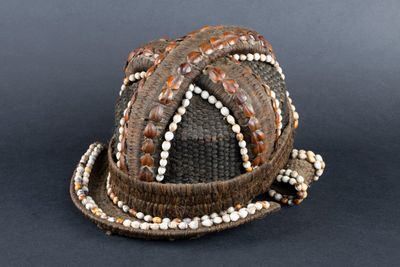 a brown hat with white beads on it on a black surface