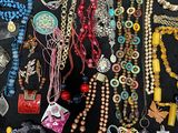 many different necklaces and bracelets laid out on a table