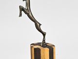 sculpture en bronze représentant une femme sautant par-dessus un bloc de bois