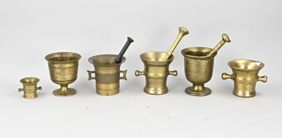 plusieurs types de mortiers en laiton et d'autres objets posés sur une surface blanche