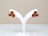une paire de boucles d'oreilles en rubis et or, posée sur un socle blanc