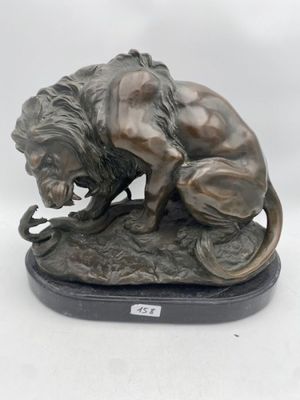 statue of a lion on a rock with a snake in its mouth