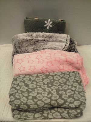 quatre couvertures sur un lit, avec un sac à main posé dessus