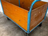 a wooden cart with a blue handle on a cement floor