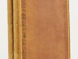 an old book with a brown cover sitting on top of a white table