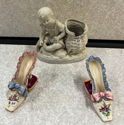 une petite statue représentant un bébé assis à côté d'une paire de chaussures
