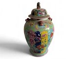 un vase coloré muni d'un couvercle, posé sur une surface blanche