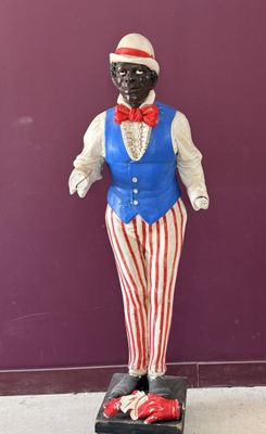 une statue représentant un homme portant un gilet rouge, blanc et bleu et un nœud papillon