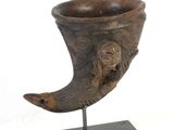 un grand objet en forme de corne posé sur un socle, sur fond blanc