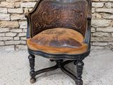 une vieille chaise avec une assise en cuir marron, posée devant un mur de pierre