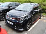 des voitures garées sur un parking devant des buissons et des arbres