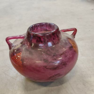 a purple vase sitting on a table with a red handle