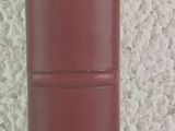 un livre rouge posé sur une table à côté d'un vase