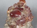 une petite figurine représentant un Bouddha souriant assis sur un rocher
