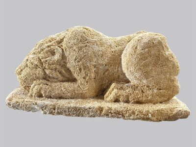 une sculpture en pierre représentant un chien couché par terre