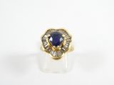 a close up of a gold ring with a blue sapphire and baguets