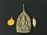 a close up of a gold pendant and a silver pendant on a black surface