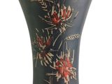 a black vase with red flowers on it on a white background