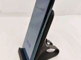 the back of a black cell phone on a stand on a white surface