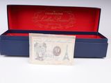 an old french bank note in a blue box on a white surface