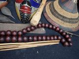 a wooden bead necklace with a mask on it next to other items