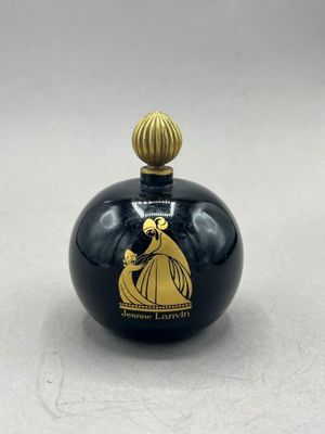 an image of a black and gold perfume bottle on a white surface