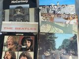 Plusieurs albums des Beatles sont posés sur un lit recouvert d'un drap blanc