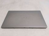 a silver laptop sitting on a bed with a white sheet